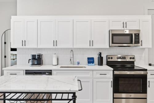 a white kitchen with white cabinets and a microwave at The Corbin 1302 - The Yale in Fort Worth
