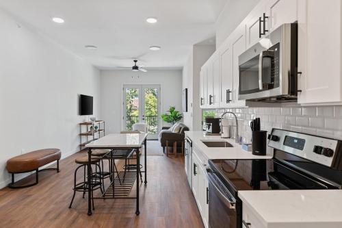 a kitchen with white cabinets and a table and chairs at The Corbin 1302 - The Yale in Fort Worth