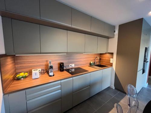 une cuisine avec des armoires blanches et un comptoir en bois dans l'établissement Appartement neuf avec jardin et parking dans résidence calme, à Villeneuve-lès-Avignon