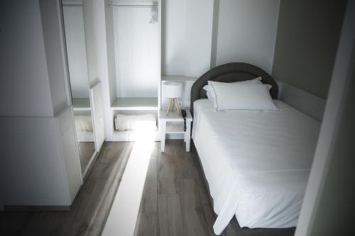 a small bedroom with a white bed and a window at Hotel Adriatico in Tricase