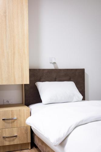 a bedroom with a white bed and a wooden headboard at Restoran & Motel Manjež in Bijelo Polje