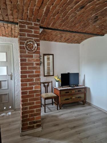 a living room with a television and a brick wall at Stara Kuźnia Radków in Wünschelburg
