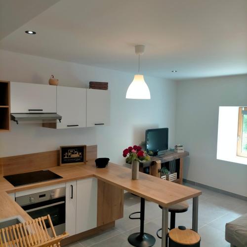 Il comprend une cuisine avec une table en bois et un bureau. dans l'établissement L'Ecrin de 40m2 pour 2 personnes, à Eygliers