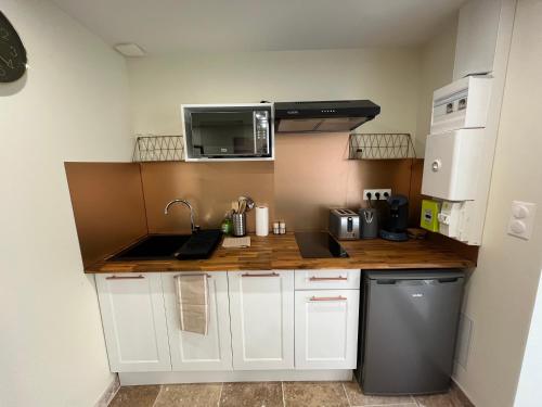 une petite cuisine avec des armoires blanches et un micro-ondes dans l'établissement L'Oasis de la pyramide, à Vienne