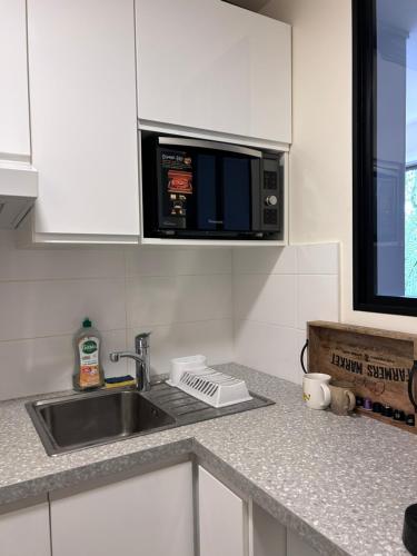 un comptoir de cuisine avec un évier et un micro-ondes dans l'établissement Face au Bois de Boulogne et proche Champs-Élysées, à Neuilly-sur-Seine