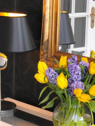 a vase of yellow and purple flowers in front of a mirror at Beachlands Hotel in Weston-super-Mare