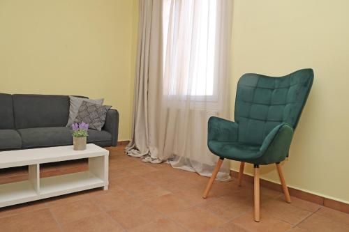 a living room with a green chair and a couch at Virginia's guest house in Ermoupoli