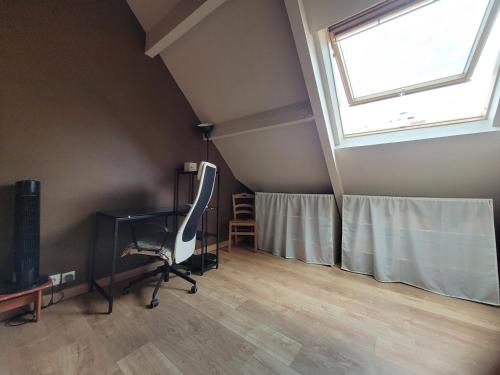 Cette chambre mansardée comprend un bureau et une fenêtre. dans l'établissement Chambre cosy - lit 2 places, à Sannois