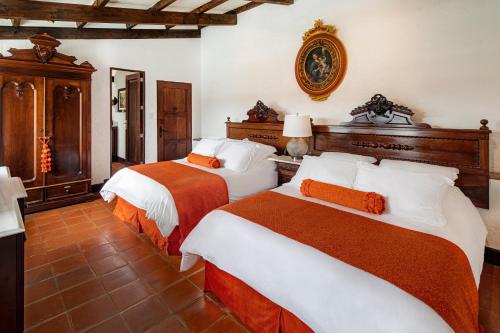 a bedroom with two beds with orange and white sheets at Las Cruces Boutique Hotel in Antigua Guatemala