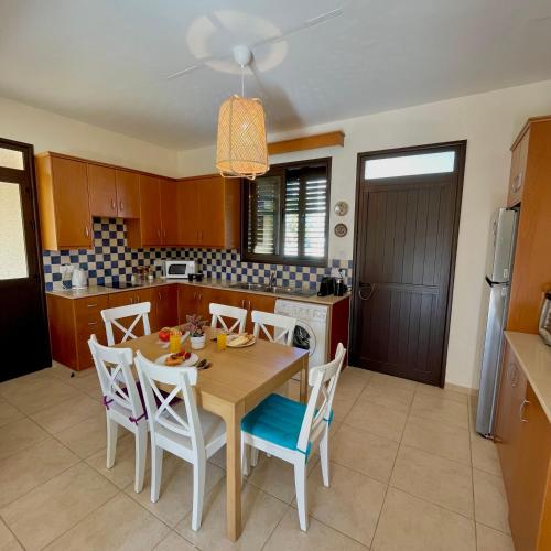 a kitchen with a wooden table and chairs in a kitchen at Pervolina countryside by the sea in Pervolia