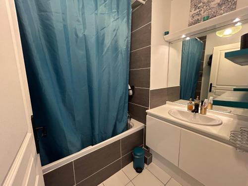 La salle de bains est pourvue d'un rideau de douche bleu et d'un lavabo. dans l'établissement Charmant T3 proche gare et plages Toulon PARKING PRIVÉ, à Toulon