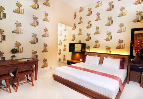 a bedroom with a bed and a desk and a wall with pictures at Batikan de Ville House in Yogyakarta