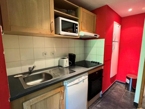 une petite cuisine avec un évier et un micro-ondes dans l'établissement Résidence Le Centaure - Studio pour 2 Personnes 731, à Aime La Plagne