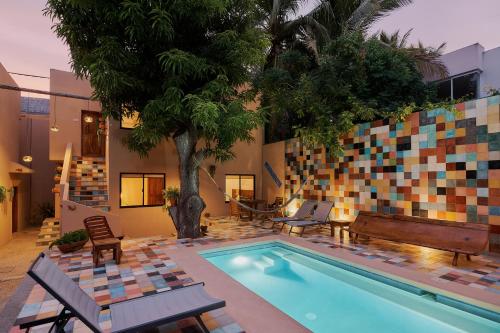 a pool with chairs and a palm tree next to a building at Casa Mosaicos - Adults only in Puerto Escondido