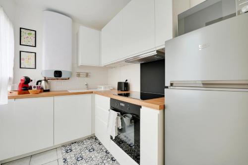 - une cuisine blanche avec des placards blancs et une cuisinière dans l'établissement Le Matisse - 6 p - Entre Paris & Disney - Métro 8, à Maisons-Alfort
