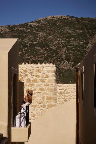 a woman sitting on a balcony looking out of a building at Manili Boutique Suites & Villas in Archanes