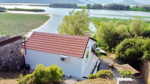 a small house with a red roof next to a river at Apartman Skadarsko jezero bay in Vranjina