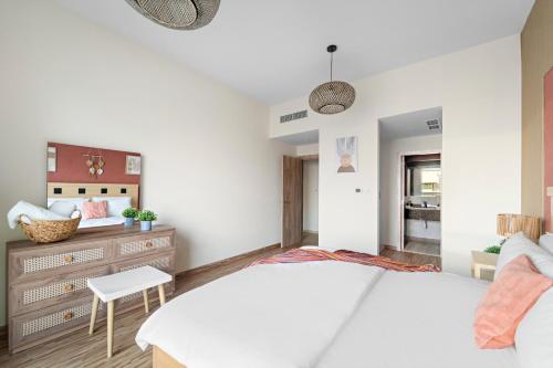a bedroom with a white bed and a chair at Aesthetic Beach Apartment , Sleeps 6, Pool, Gym & Waterfront Views in Dubai