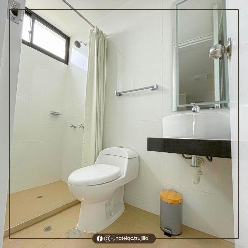 a white bathroom with a toilet and a sink at Hotel QC in Trujillo