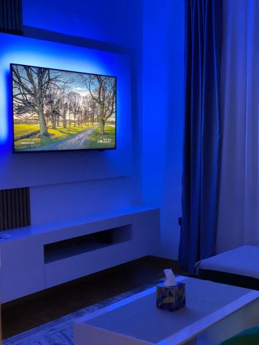 a living room with a tv on a blue wall at Sarajevo Luxury Apartment - 50 m from Old Sarajevo Clock Tower in Sarajevo