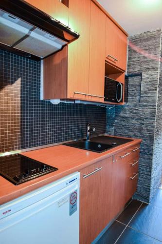 une cuisine avec des armoires en bois et un évier dans l'établissement Résidence L'aconcagua - Studio 2 personnes - ACONCAGUA - PLAGNE CENTRE MAE-4671, à La Plagne Tarentaise