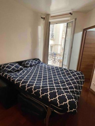 - un lit avec une couette bleue et blanche et une fenêtre dans l'établissement Appartement calme paris, à Paris