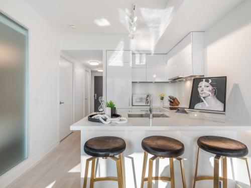 a kitchen with white cabinets and stools at a counter at Hazelton Suites - Yorkville - Indoor Pool & Hot Tub in Toronto