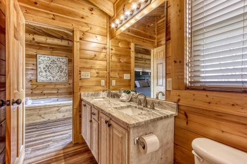 een badkamer in een blokhut met een wastafel en een bad bij Dream Come True #555 in Pigeon Forge