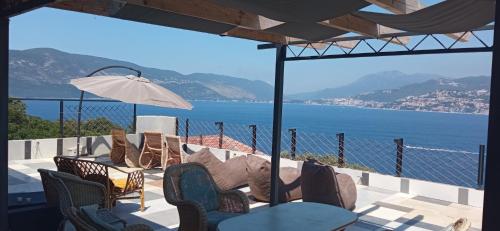 a patio with chairs and tables and a view of the water at Casa de Laza Apartments in Herceg-Novi