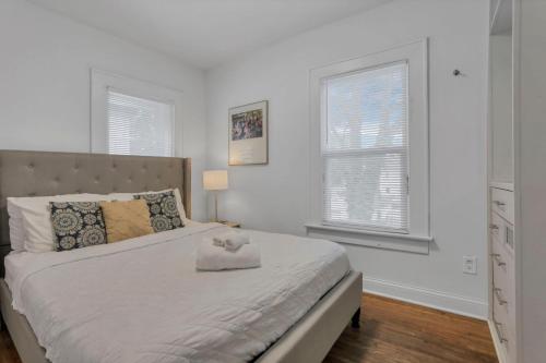 a bedroom with a large bed with white walls and windows at Housepitality - The Maynard Manor in Columbus