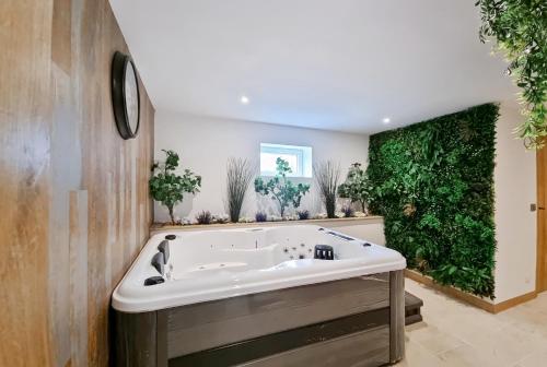 a bath tub in a bathroom with green plants at les piafs du der 1 in Joncreuil