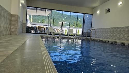 a swimming pool in a building with chairs in it at Luxury Milan Mountain Ponoramic Villa, indoor heated pool and jacuzzi with mountain view in Gabala