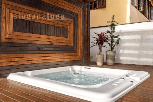 a bath tub with water in it on a wooden floor at Ogram Houses - Com jacuzzi a 3min da praia in Imbituba