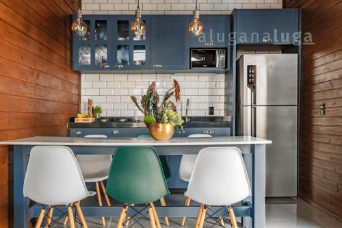 a kitchen with a counter with four chairs and a refrigerator at Ogram Houses - Com jacuzzi a 3min da praia in Imbituba