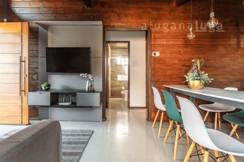 a living room with a table with chairs and a television at Ogram Houses - Com jacuzzi a 3min da praia in Imbituba