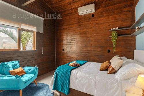 a bedroom with a bed and a blue chair at Ogram Houses - Com jacuzzi a 3min da praia in Imbituba