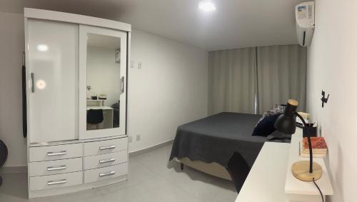 a bedroom with a bed and a dresser and a mirror at Caminho do Mar - Apartamento com excelente localização in Rio das Ostras
