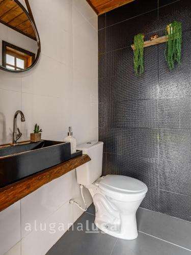 a bathroom with a white toilet and a sink at Ogram Houses - Com jacuzzi a 3min da praia #01 in Imbituba