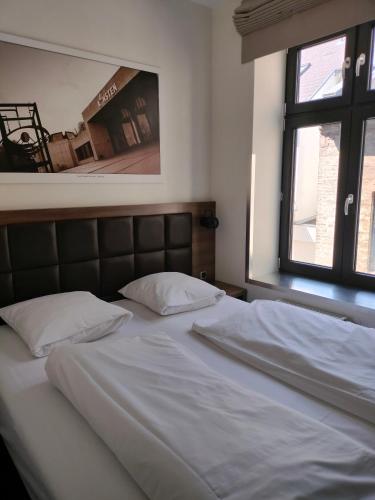 a bed with white sheets and pillows in a bedroom at Hotel Jomfru Ane in Aalborg