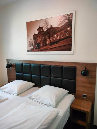 a bedroom with a bed with a picture above it at Hotel Jomfru Ane in Aalborg
