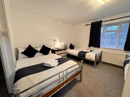 a bedroom with two beds and a window at All Seasons Gatwick Guest House & Parking in Horley
