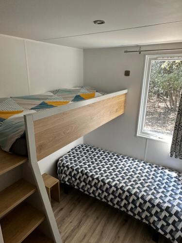 une chambre avec un lit superposé et une fenêtre dans l'établissement Mobilhome dans écrin de verdure, à Greffeil
