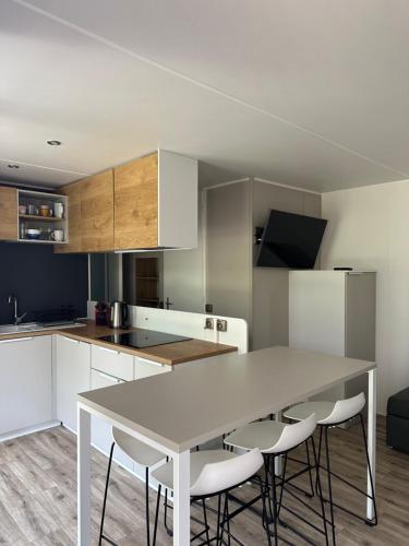- une cuisine avec une table blanche et des chaises blanches dans l'établissement Mobilhome dans écrin de verdure, à Greffeil