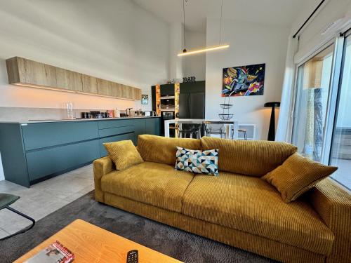 un salon avec un canapé et une cuisine dans l'établissement T3 Neuf Terrasse XXL Parking Privé Classé 4 étoiles, à Anglet