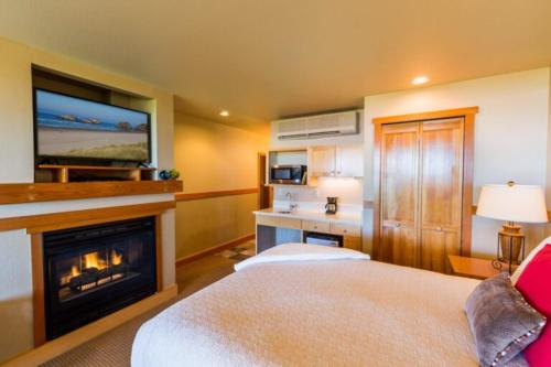 a bedroom with a bed with a fireplace and a tv at The Ocean Lodge in Cannon Beach