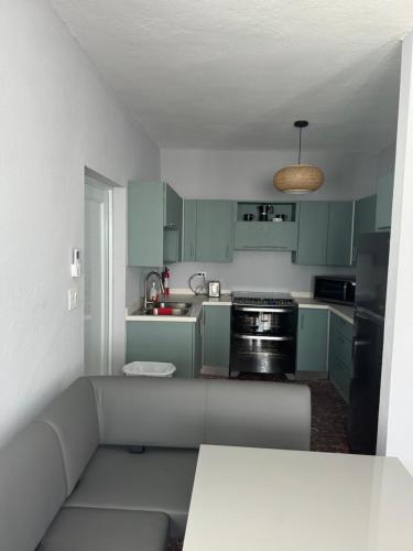 a small kitchen with green cabinets and a couch at Casa Morales in Vieques