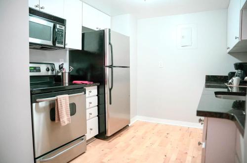 a kitchen with a stainless steel refrigerator and a wooden floor at Cozy Apartment Downtown in Stamford