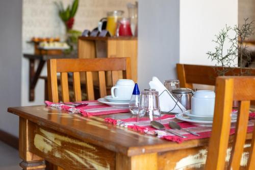 a wooden table with a red table cloth with plates and utensils at Pousada Rubi in Abraão