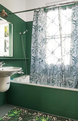 a green bathroom with a shower curtain and a sink at Villa Plater in Olsztyn