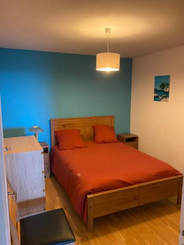- une chambre dotée d'un lit avec des draps orange et un mur bleu dans l'établissement Clair Matin T3, à Six-Fours-les-Plages